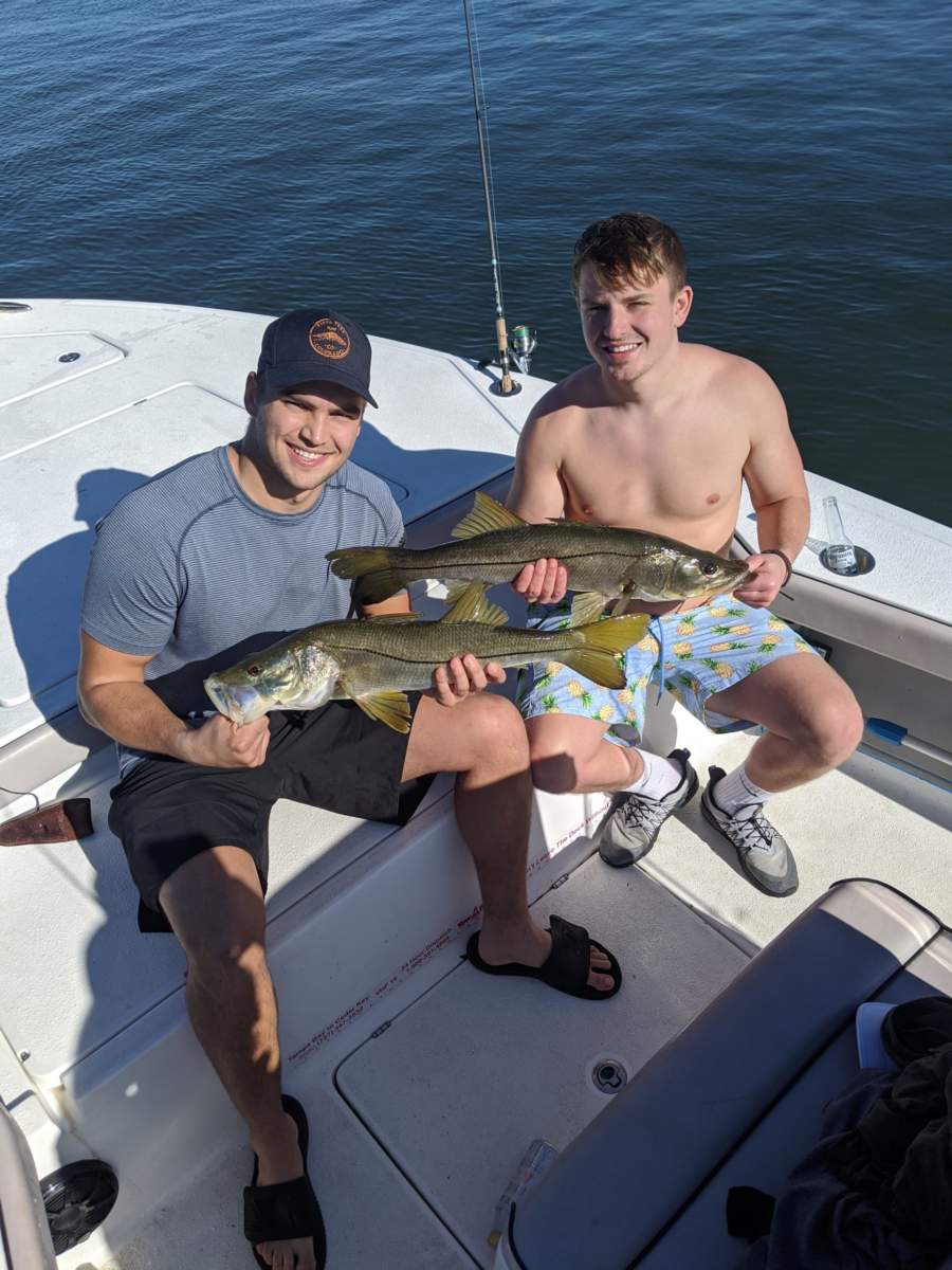 a picture of two fisherman each holding a snook they caught in tampa bay